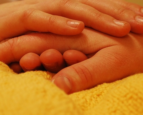 Eine Pflegerin greift die Hand eines Kranken.